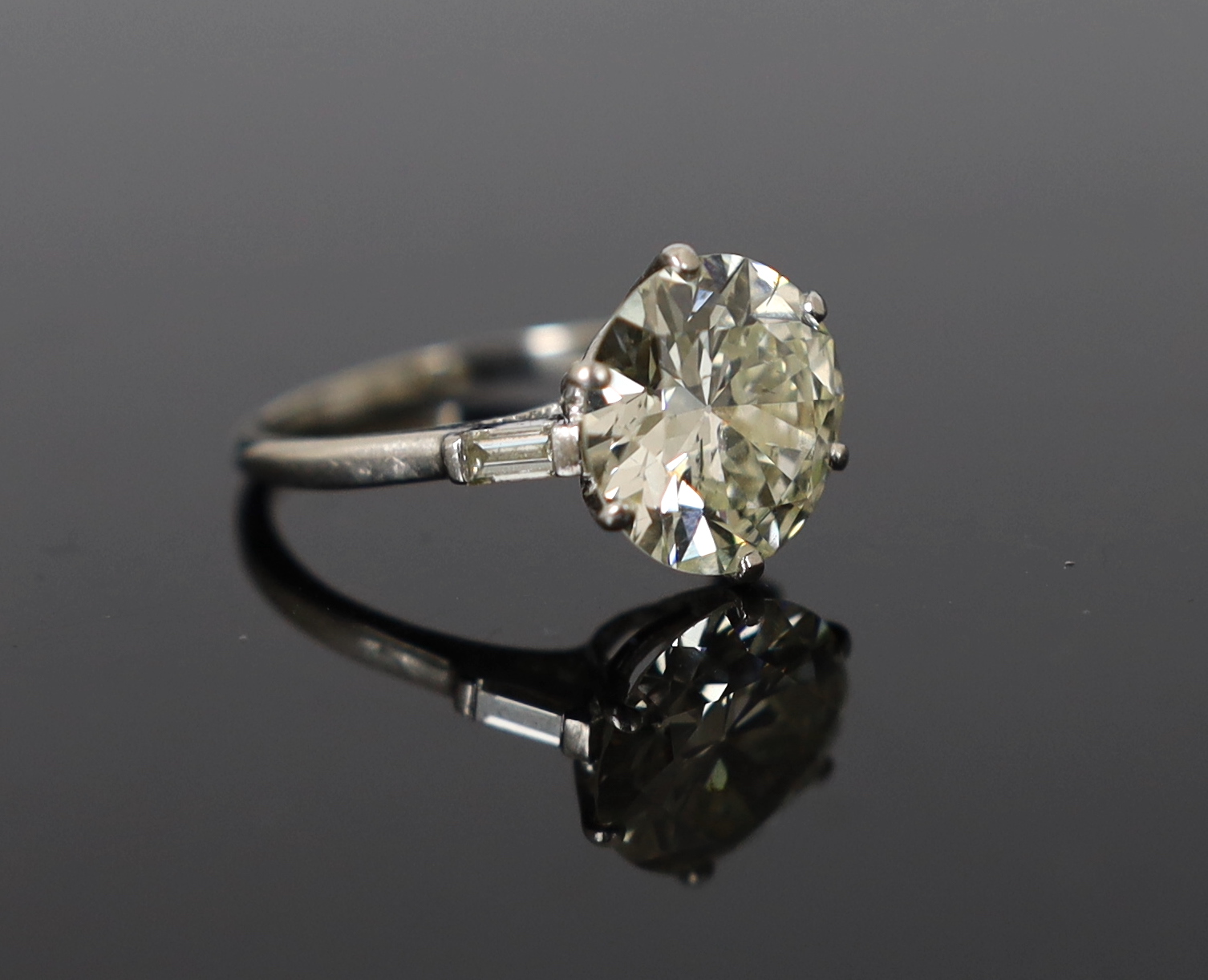 A platinum and single stone diamond set ring, with baguette cut diamond set shoulders